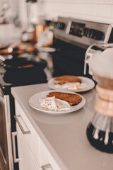 Breakfast on the kitchen countertop. Fresh brewed coffee. Fried eggs, bread toasts on plates. Morning routine. Meal before work. Quick food brunch. Lifestyle home. Brown, white. Modern life.