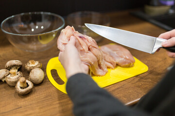 woman cooking chicken meat on yellow desk at kitchen