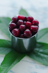 Cherries in a steel mug on a wooden background