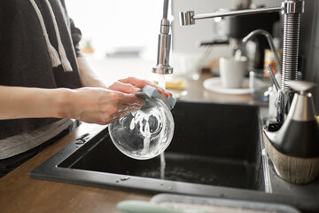 Young woman wash dishes and glass at kitchen