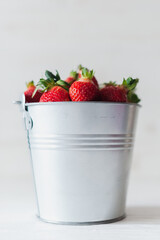 Juicy fresh strawberries in a metal bucket on a white background