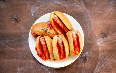 Halloween food. Homemade hot dogs with bloodied fingers on a wooden table for Halloween. Side view....