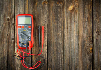 Digital multimeter on a wooden table. Copy space.