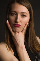 portrait of a brunette on a black background, shows a hand gesture. Rock'n'roll.