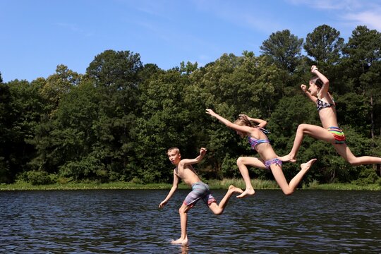 Three kids celebrating summer by jumping into the lake