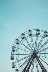 A long distance view of a a vintage Ferris Wheel fairground ride with blue sky background and copy space