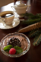 Festive chocolate mousse dessert with rapsberry, mint and chocolate cookie with coffee and pine cone