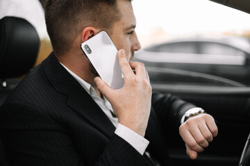 Handsome caucasian businessman driver inside in vehicle  with coffee and gadget and check mail and talking with partners