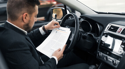 Handsome caucasian businessman driver inside in vehicle  with coffee and gadget and check mail and talking with partners