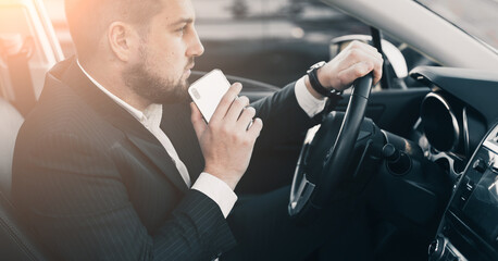 Handsome caucasian businessman driver inside in vehicle  with coffee and gadget and check mail and talking with partners