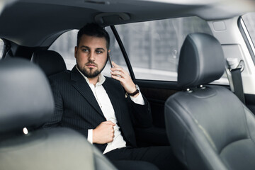 Fototapeta na wymiar Handsome caucasian businessman driver inside in vehicle with coffee and gadget and check mail and talking with partners