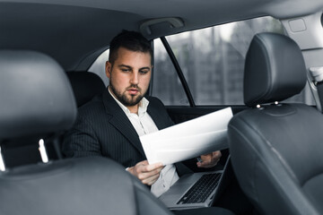 Handsome caucasian businessman driver inside in vehicle  with coffee and gadget and check mail and talking with partners