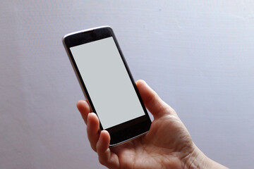 hand holds mobile phone with blank white screen, mock up
