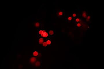 Red hexagonal bokeh lights on dark background from unfocused macro, created with red fairy lights...