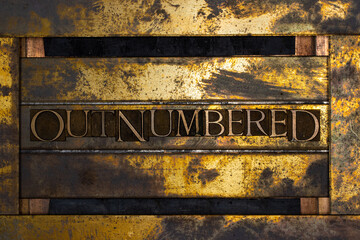 Photo of real authentic typeset letters forming Outnumbered text on vintage textured silver grunge...