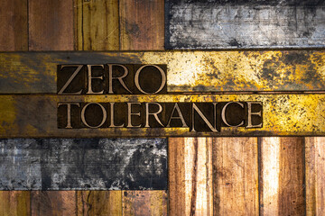 Photo of real authentic typeset letters forming Zero Tolerance of text on vintage textured silver grunge copper and gold background
