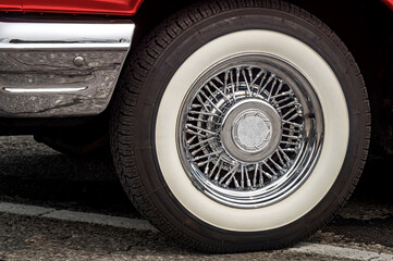 Shiny chrome spoked wheel disk with painted in white tire of red old timer luxury sports car