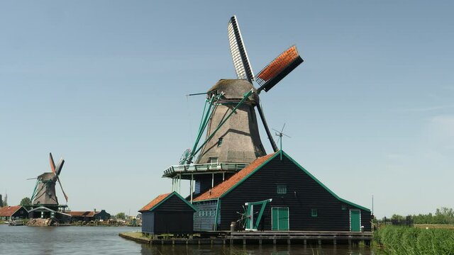 Windmills and farmhouse by the water in Holland, the Netherlands.