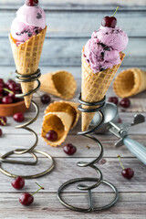 Two cherry ice cream cones on metal spiral stands ready for eating.