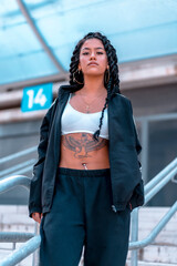 Obraz premium Urban session to trap dancer, with a young brunette of Latin ethnicity with braids, with unbuttoned black sweatshirt