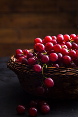 Close-up view of juicy grapes in wicker bowl. Healthy grapes in wicker basket on table with wooden background.