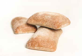 White square ciabatta bread on a white background. Food on the table, extract, sunrise kitchen, delicious snack.