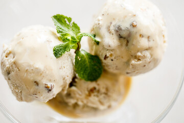 Creamy ice cream with nuts and mint leaves in a glass cup. Close-up. Macro photo. Selective Focus....