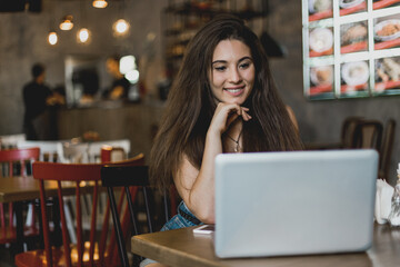 Business woman working on a laptop and drinking coffee in a cafe.