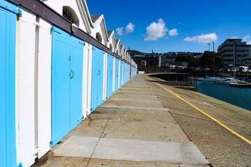 Obraz premium A boat garage with bright blue gates at the harbor of Wellington, capital of New Zealand, North Island, on a sunny day. 