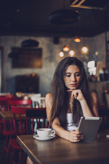 Business woman using tablet and drinking coffee in a cafe.