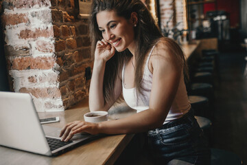 Business woman working on a laptop and drinking coffee in a cafe.