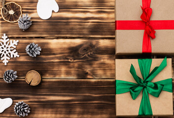 Fototapeta premium Christmas and New Year. Wooden dark flat lay frame with gifts, Christmas toys and cones. Copy space.