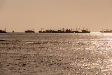 Beautiful orange sunrise is on the beach by the sea with black ship silhouettes