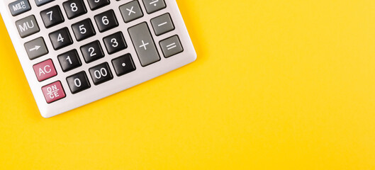 Large silver calculator with gray and black buttons on a yellow background. Conceptual photo of...