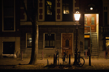 glimpse of a desert footpath in a residential district of Amsterdam city illuminated at night, bicycles parked in front of a house, Netherlands, Holland, Europe.