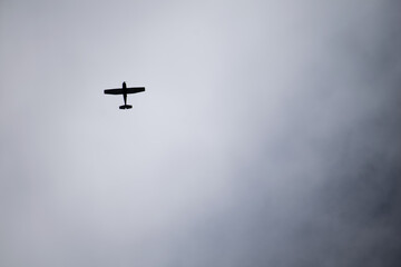 The silhouette of the plane. Small plane flying in the sky with black clouds