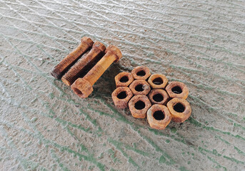 Old, rusty nuts and bolts lie on a metal background. Rubbish and waste at an industrial plant. Photography, concept.