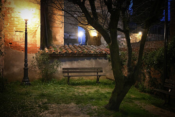 Empty bench at twilight, illuminated by the light of a lamppost in a lonely garden in the...