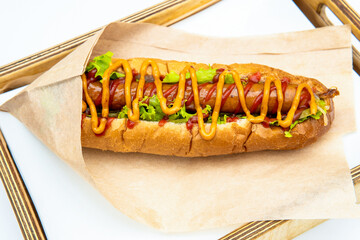 Hot dog with salad and cucumbers with tomato ketchup and mustard on white background. Tasty and beautiful fast food on a light back.