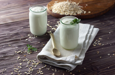 Natural yogurt in little jar with muesli and fresh mint leaves. Healthy breakfast concept. Wooden background, close up.