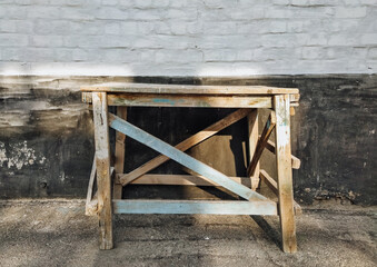 Home-made wooden scaffolding stand on the ground against a background of a wall of bricks. Photography, concept.