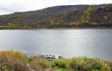 Podkamennaya Tunguska river and motor boats near the shore in autumn.