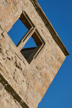 Brown window in a brick castle with a blue sky, sloping but symmetrical. Germany.