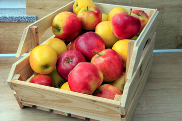 Fresh apples, stored in a wooden box.