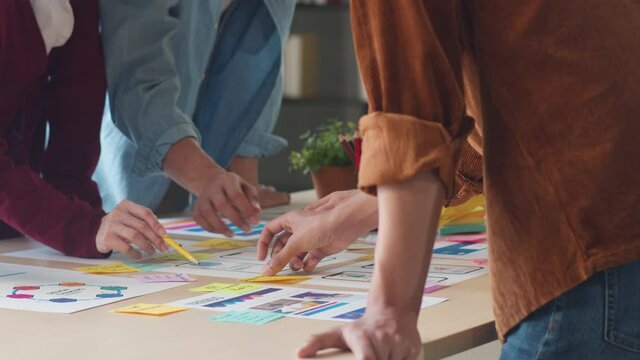 Asian businessmen and businesswomen meeting brainstorming ideas about creative web design planning application and developing template layout for mobile phone project working together in small office.