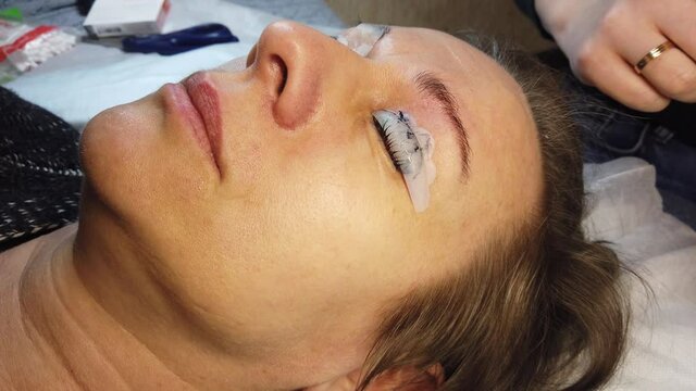 Beauty treatment. Beautician procedure of laminating eyelashes. Fixing of eyelashes. Closeup face.