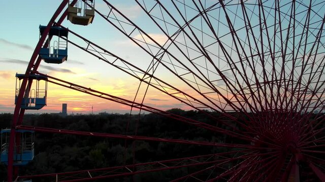 Close Up Aerial View of Ferris Wheel in Abandoned Amusement Park and Sunset Skyline in Background. Spreepark, East Berlin, Germany