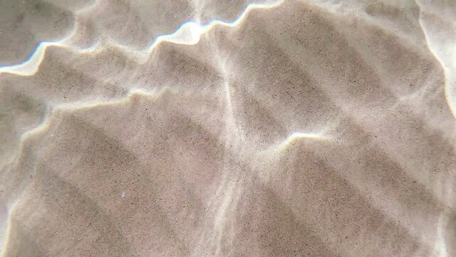 Underwater scene of sea ripple water on white sand .