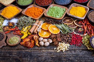 Many colorful spices, herbs and dried fruits on the wooden rustic table