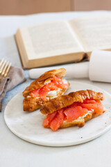 Breakfast with croissant, cream cheese and smoked salmon. Old book on the background.
